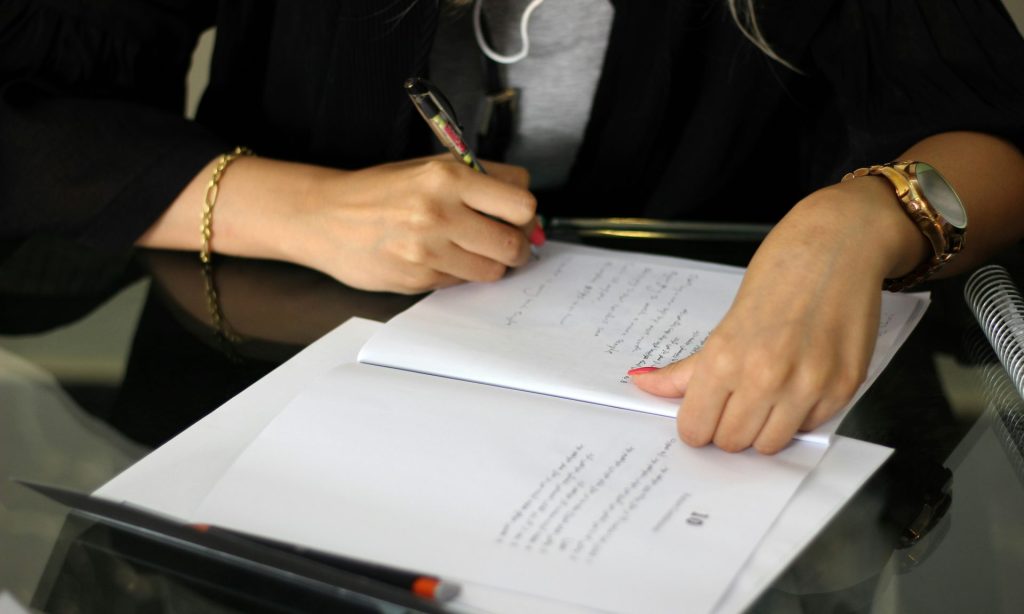 une personne écrivant sur une feuille de papier