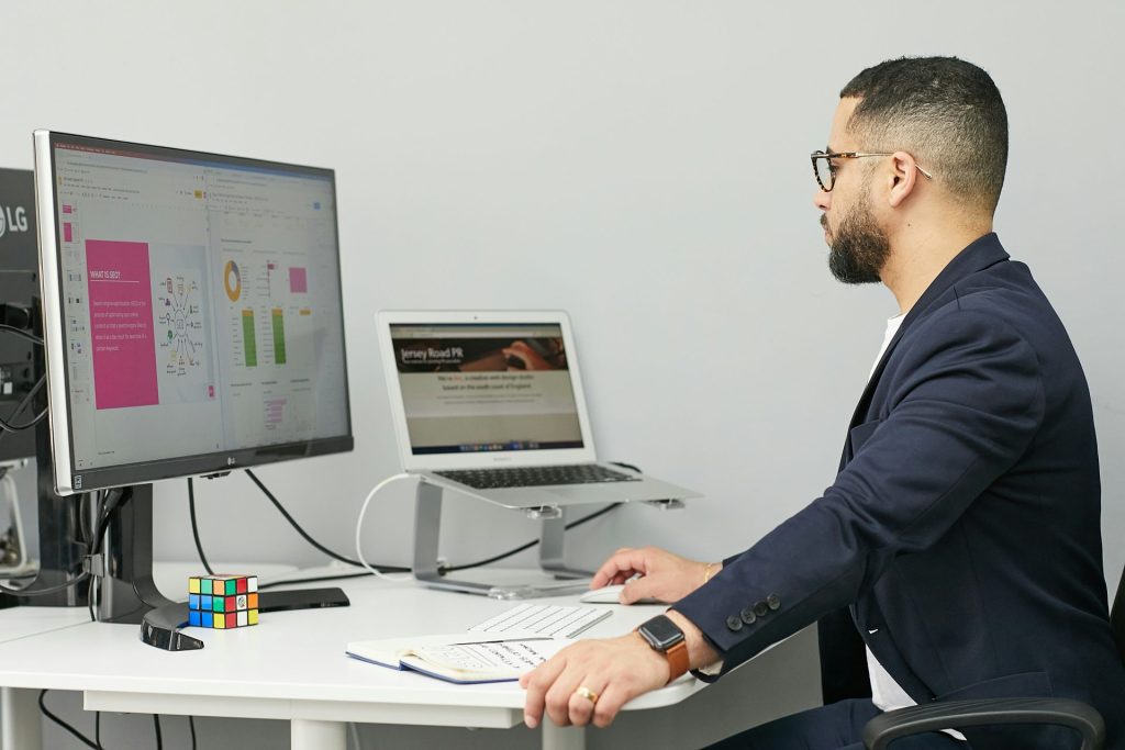 un homme assis à un bureau avec un ordinateur portable et un ordinateur